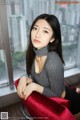 A woman sitting on a red chair in front of a window.