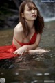 A woman in a red dress sitting in the water.