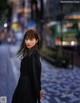 A woman in a black dress standing on a city street.