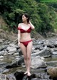 A woman in a red bikini standing in a stream.