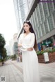 A woman in a white dress standing on a city street.