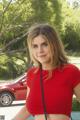 A woman in a red top standing next to a red car.