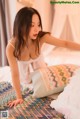 a woman laying on top of a bed next to pillows